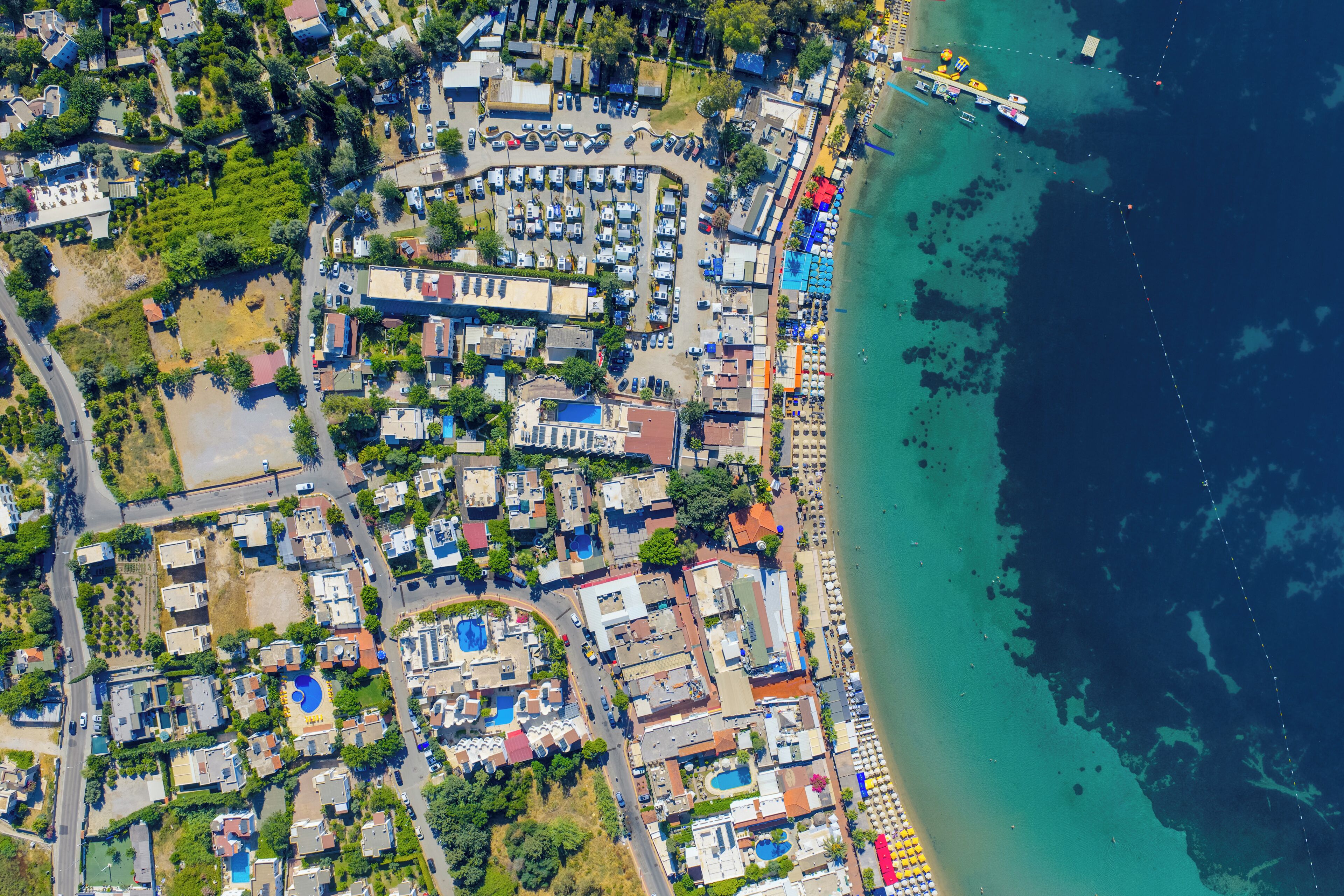 An aerial view of a coastal area with buildings, roads, and a beach.