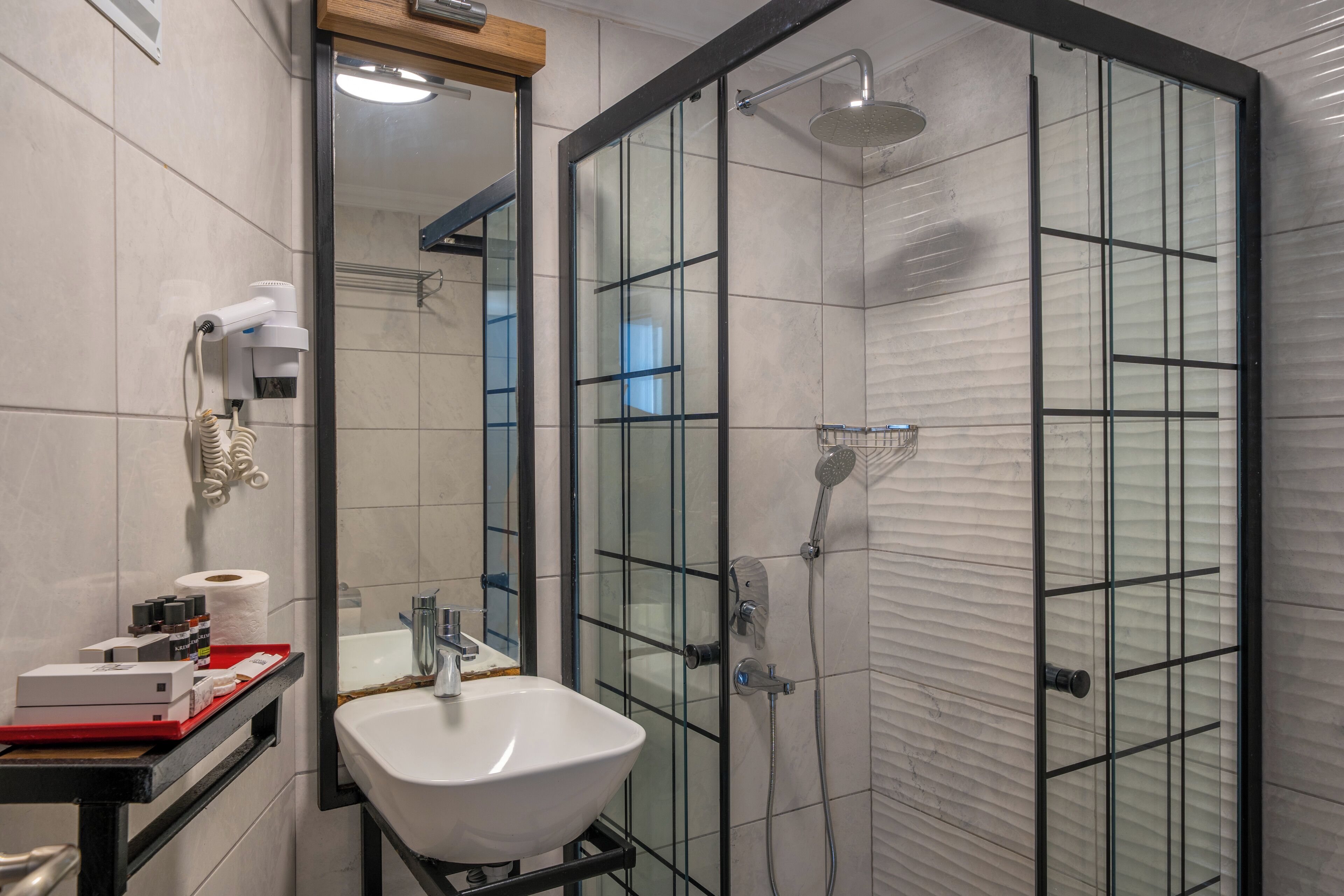 A modern bathroom with a glass-enclosed shower, a sink, and a mirror.