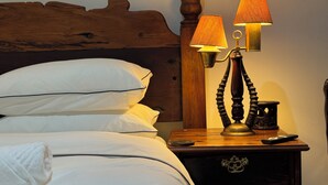A neatly made bed with white linens and pillows, a wooden headboard, a bedside table with a lamp, a remote control, and a small decorative item. - Flexistay Hotel (Cape Town)