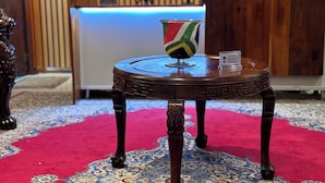 A round wooden table with a colorful glass vase and a small plaque. - Flexistay Hotel (Cape Town)