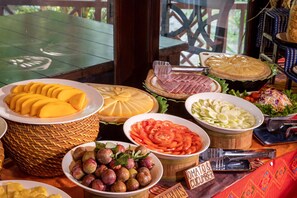 Une table de buffet proposant une variété d’aliments, notamment des tranches de mangue, du fromage, du jambon et des légumes.