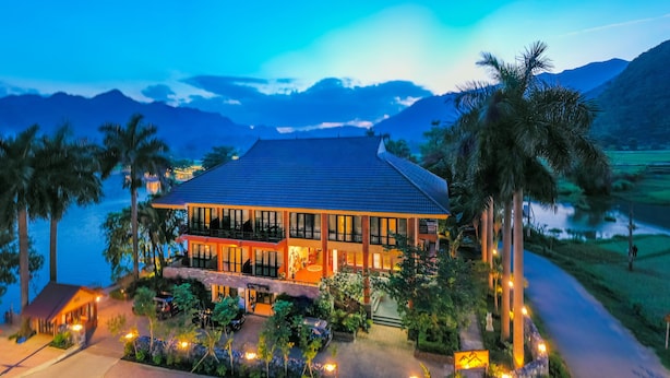 Un hotel moderno con un edificio grande, un jardín cuidado y vistas a montañas y un lago.