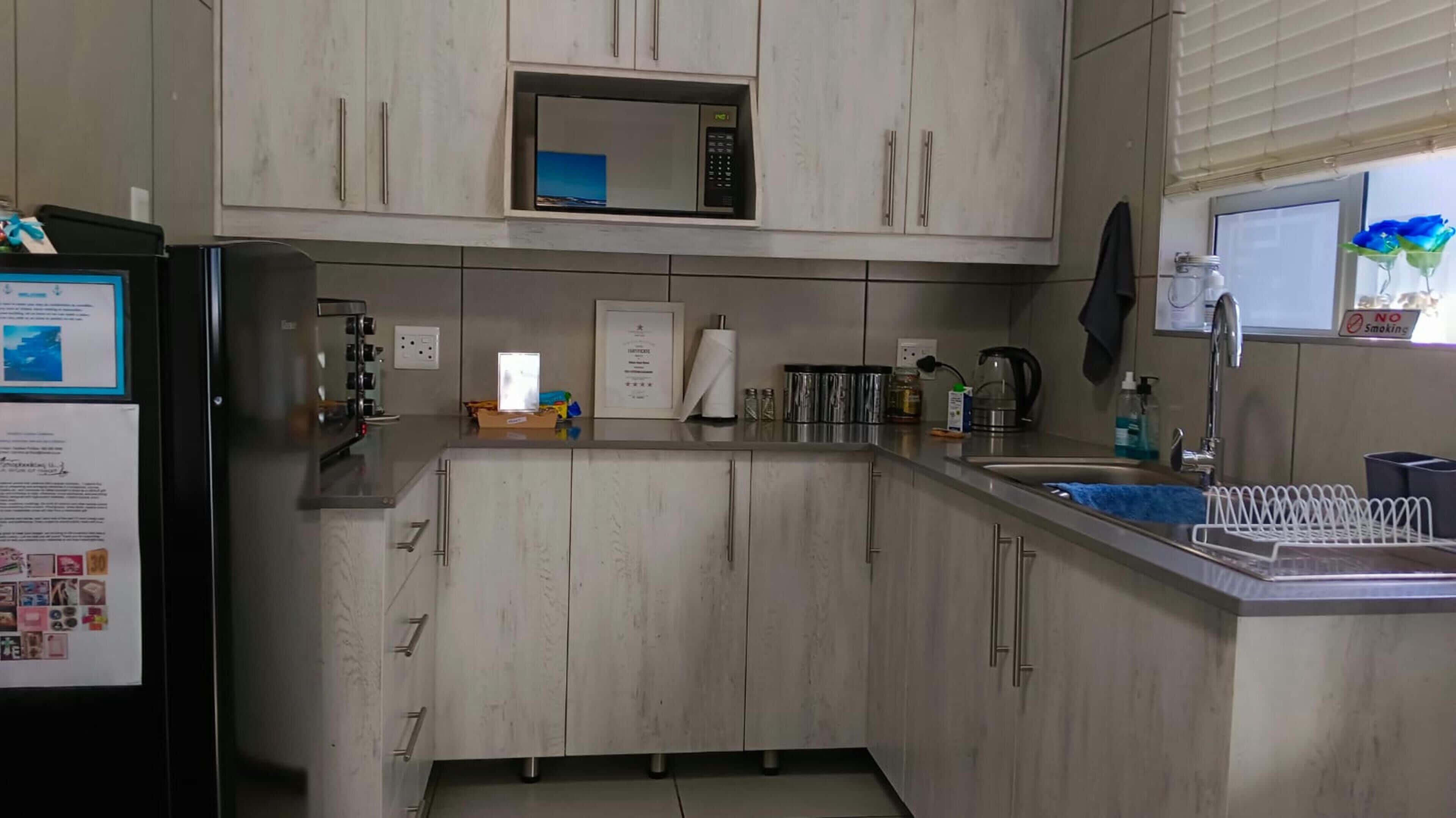 A kitchen with wooden cabinets, a microwave, a sink, and a refrigerator.