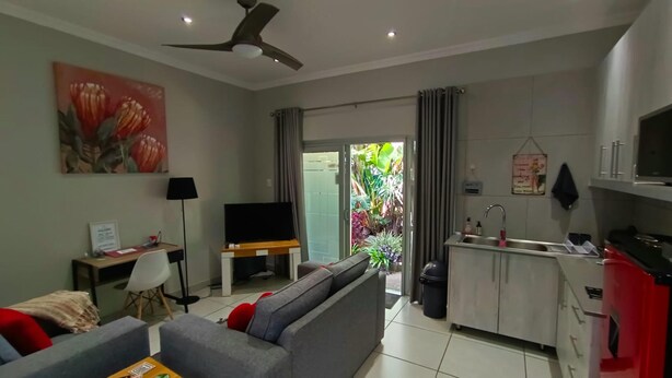 A modern living room with a sofa, TV, and a dining area with a kitchen.