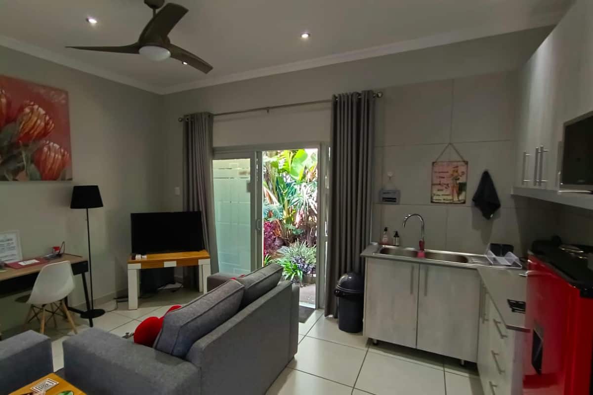 A modern living room with a sofa, TV, and a dining area with a kitchen.