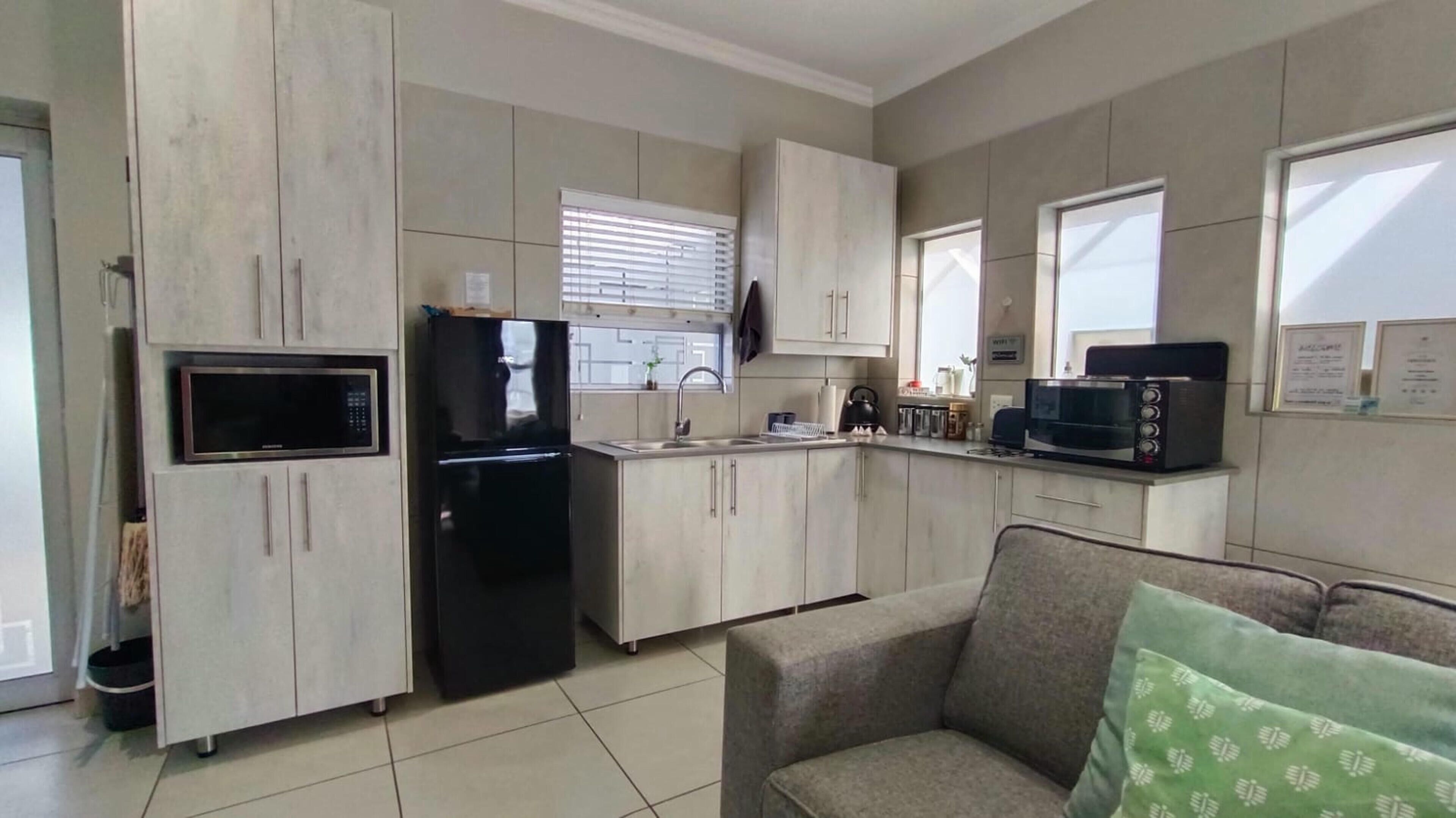 A compact kitchen with a refrigerator, microwave, and sink.