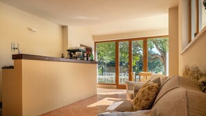 Eine moderne Küche mit integrierter Kochinsel, großen Fenstern und einer gemütlichen Sitzecke mit Sofa und Sesseln.