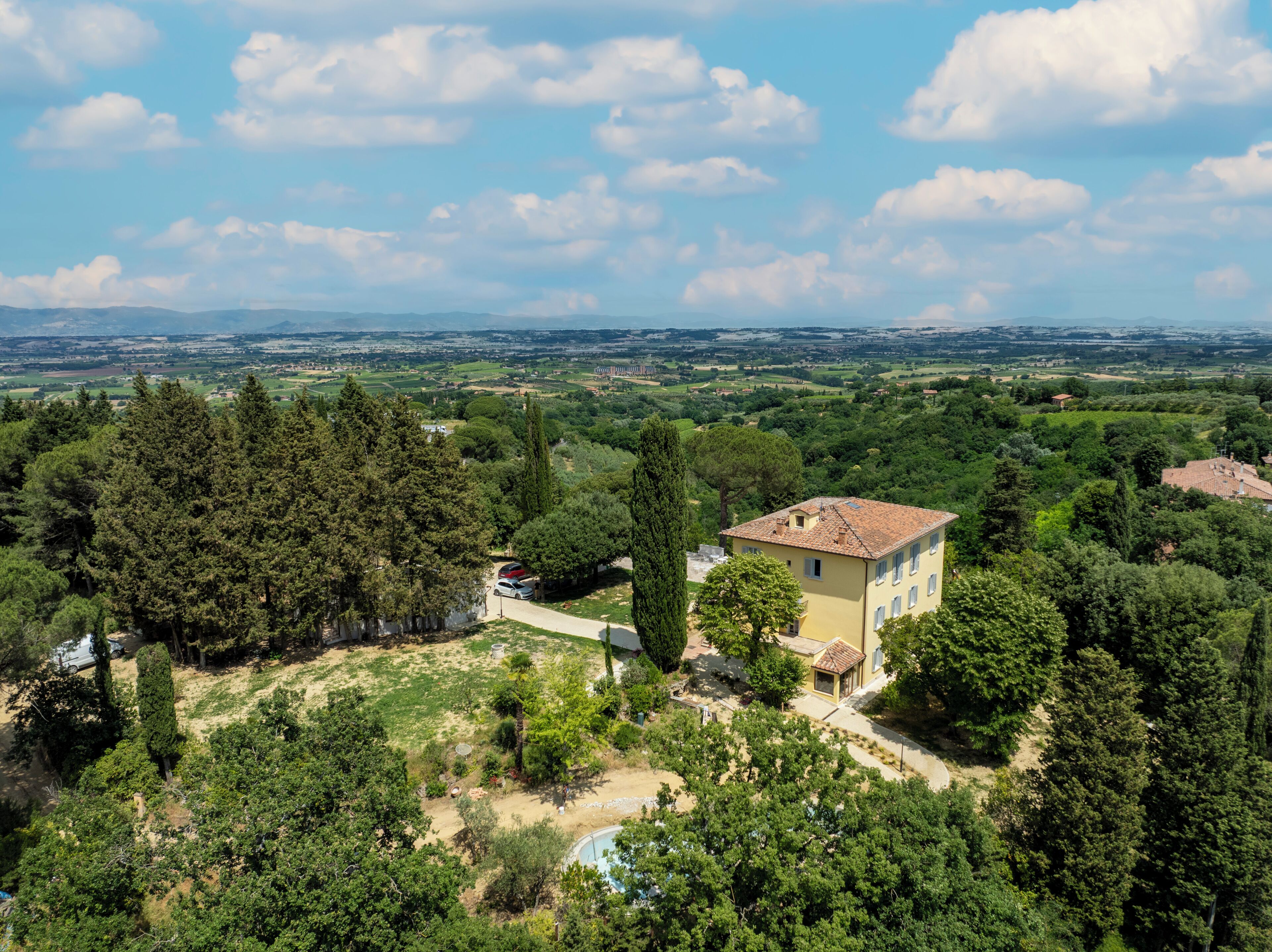 Eine Villa, umgeben von dichtem Baumbestand und einem klaren Himmel.