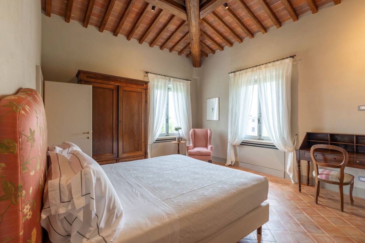 Une chambre avec un plafond en bois, un lit, une armoire, une chaise et un bureau.