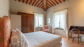 Ein Schlafzimmer mit Holzboden, einem Bett, einem Kleiderschrank, einem Stuhl und einem Schreibtisch.