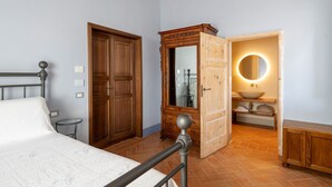Ein Schlafzimmer mit einem Bett, einem Holzschrank und einem Badezimmer mit rundem Spiegel und Waschbecken.