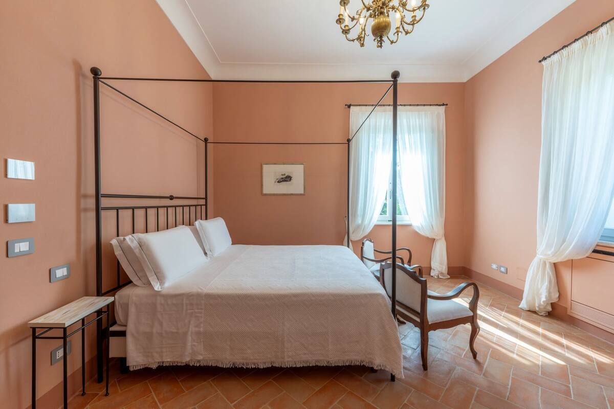 Un lit à baldaquin avec un couvre-lit blanc, une chaise en bois et un lustre.