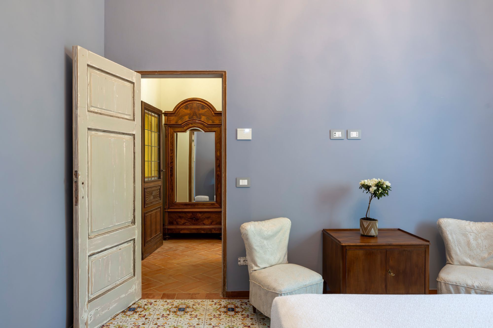 Une chambre à coucher comprenant un lit, une table de chevet, une chaise, une commode et un miroir.