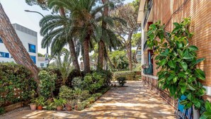 Un chemin pavé bordé d’une végétation luxuriante et d’un bâtiment en briques.