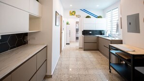 A modern kitchen with a marble countertop, stainless steel appliances, and a black backsplash.