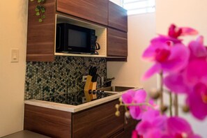 Una cucina compatta con forno a microonde, lavello e pensili in legno.