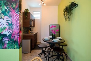 A compact kitchen with a refrigerator, a dining table with chairs, and a window providing natural light.