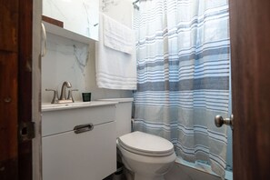 A small bathroom with a toilet, a sink, and a shower curtain.