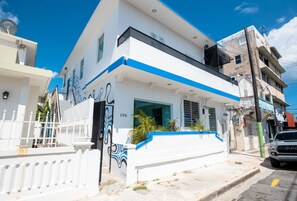 A modern two-story building with a white facade and blue trim, featuring a gated entrance and a visible number '106'.
