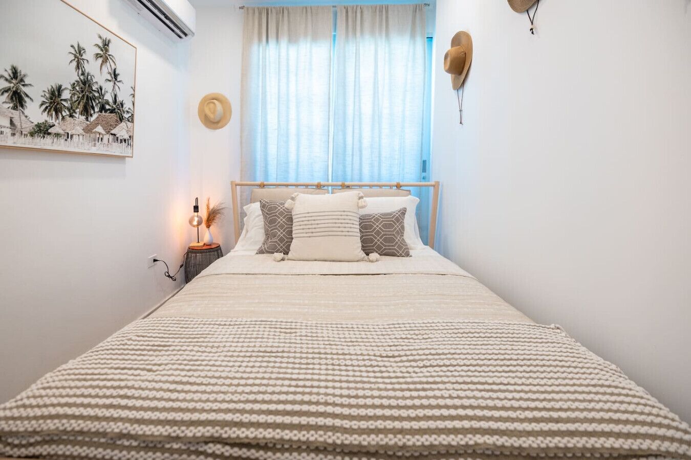 A neatly made bed with a striped bedspread, a wooden headboard, and two bedside lamps.