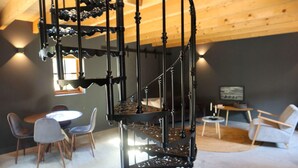 Un intérieur moderne avec un escalier en colimaçon, un coin repas et un espace salon.