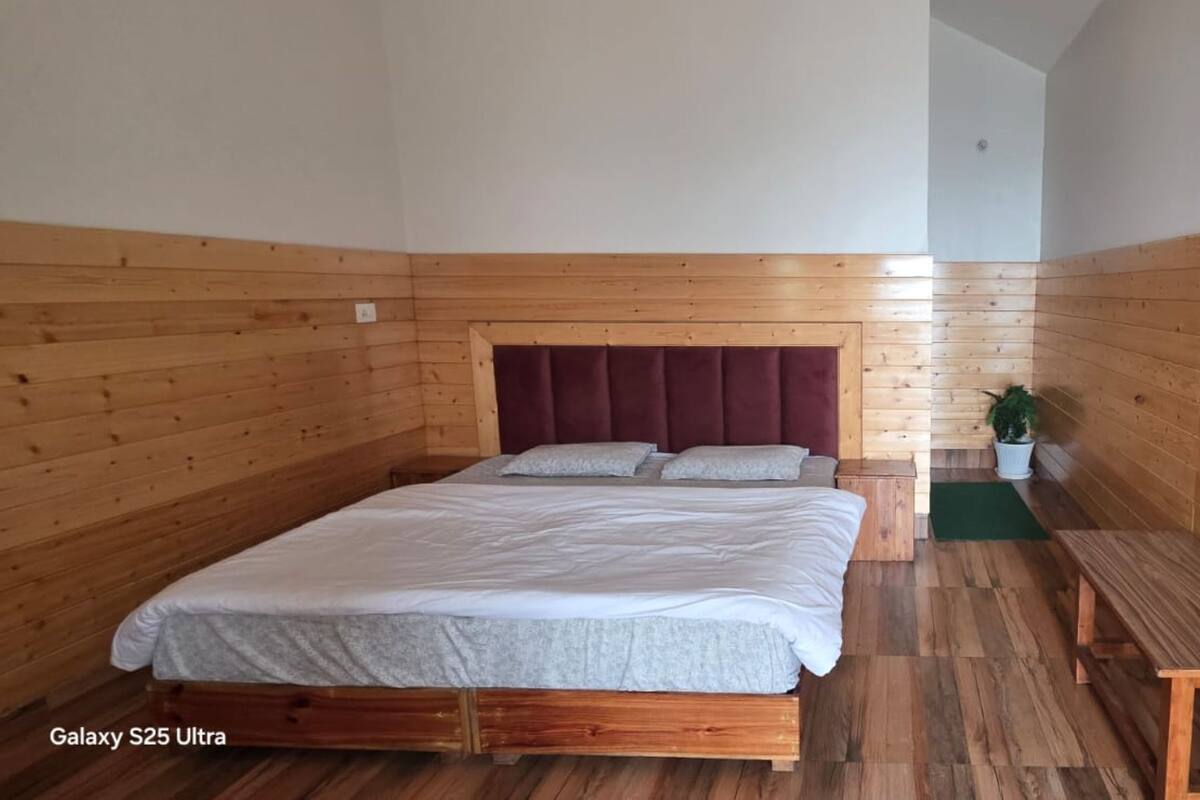 Un Galaxy S25 Ultra posé sur un lit dans une pièce aux murs et au plancher en bois.