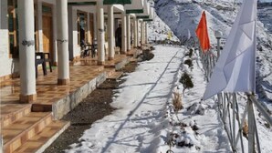 Un espacio al aire libre cubierto con un sendero nevado que lleva a un edificio con varias puertas y ventanas.