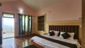 Un dormitorio con cama, cabecero de madera, ventana con cortinas y puerta que da a un espacio exterior.