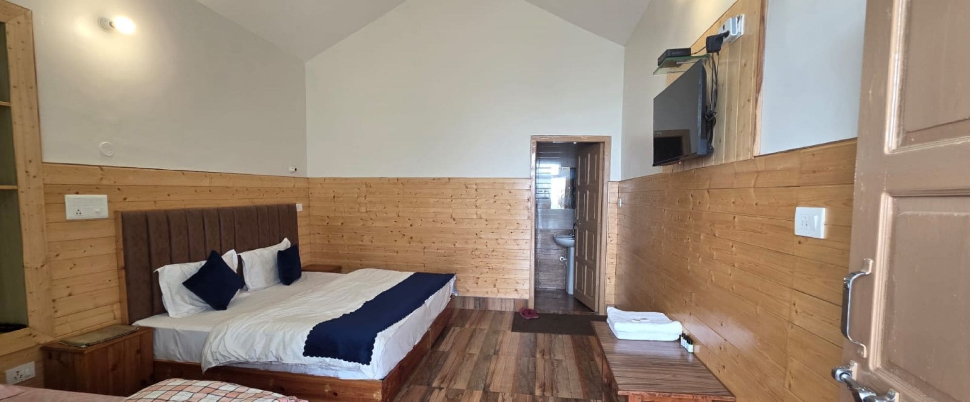 A bedroom with a wooden headboard bed, a small bedside table, and a wooden bench.
