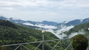 Paisaje montañoso con vistas a campos en terrazas y una barandilla con luces esféricas.