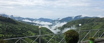 Paisaje montañoso con vistas a campos en terrazas y una barandilla con luces esféricas.