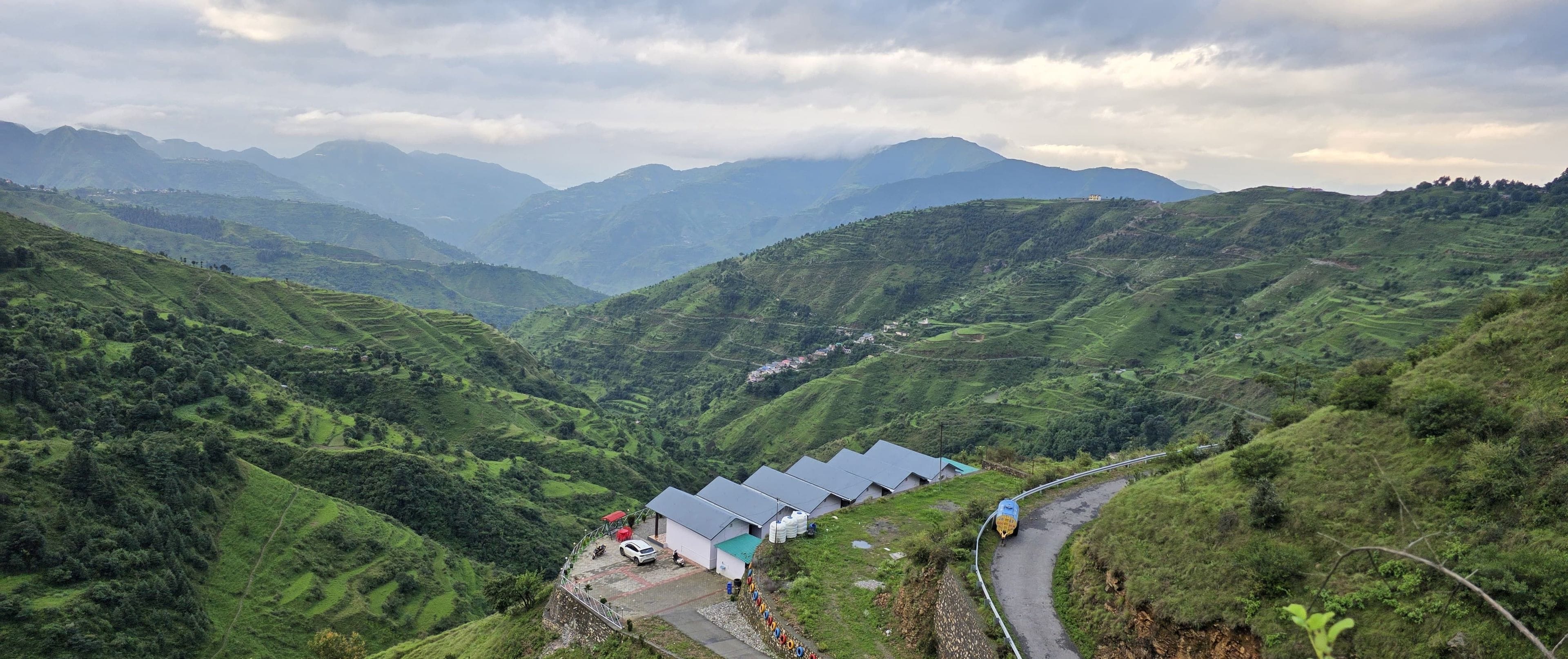 A mountainous landscape with terraced fields and a road curving through the valley.