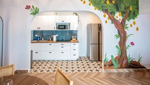 Una cocina moderna con armarios blancos, un salpicadero de azulejos azules y un gran mural de un árbol.