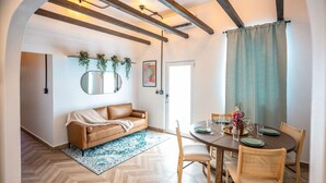 Un rincón comedor acogedor con una mesa redonda para cuatro, un sofá de cuero marrón y un piso de madera con patrón de espiga.