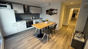 Una cocina moderna con armarios blancos, una mesa de comedor de madera y una silla negra.