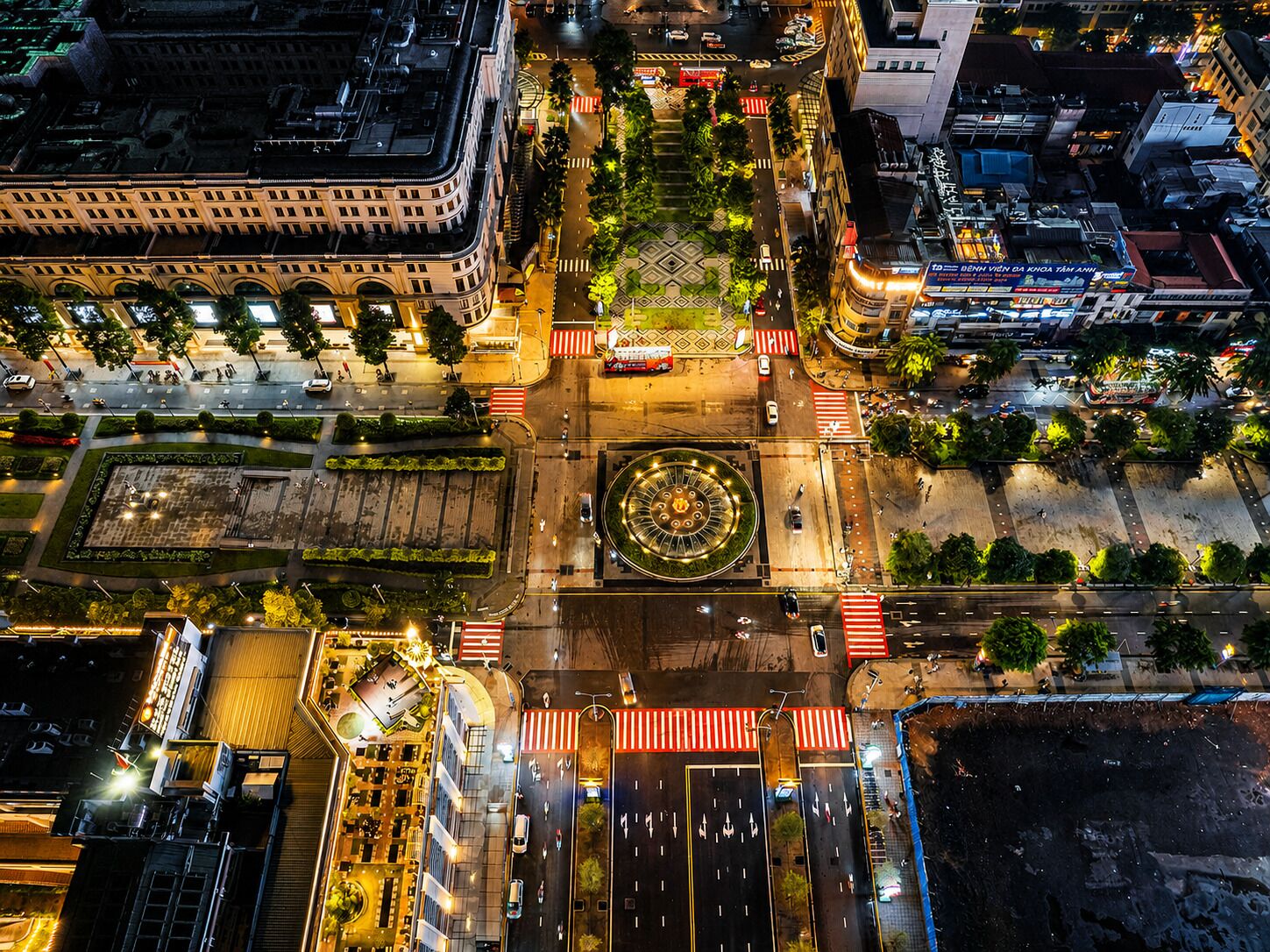 An aerial view of a city intersection with a roundabout, buildings, and roads.