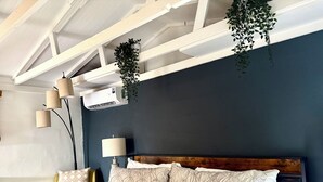 Ein Schlafzimmer mit einem Bett, Nachttischlampen, einer hängenden Pflanze und einer Klimaanlage.