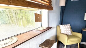Ein Zimmer mit Fenster, einem gelben Sessel, einer Holzbank und einem kleinen Hocker.