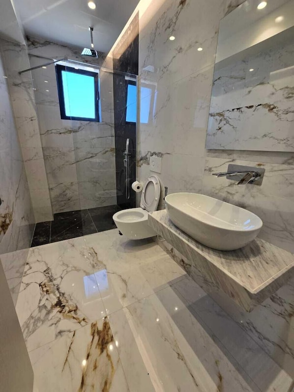 Un bagno moderno con un lavabo in marmo di grandi dimensioni, un water e una doccia.