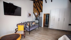 A modern living room with a sofa, a wooden coffee table, a television, and a kitchen area in the background. - Golden Casa (Mokopane)