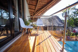 A wooden deck with two white chairs and a glass balustrade overlooking a pool and tropical scenery. - Golden Casa (Mokopane)
