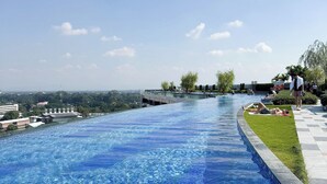 Ein Swimmingpool mit glasklarer, blauer Wasserfläche, umgeben von einer niedrigen Steinmauer und einer Rasenfläche.