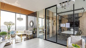 Ein moderner Arbeitsbereich mit Glastrennwand, einem Essbereich mit weißem Tisch und Stühlen und Blick auf die Stadt durch große Fenster.