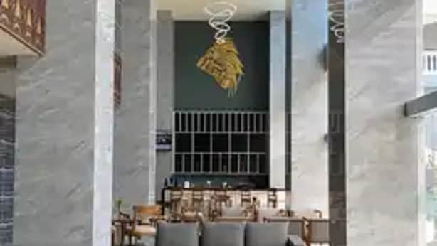 A spacious lobby with a modern grey sofa set, two black round tables, and a chandelier. - Hotel Horison Ultima Entrop (Jayapura)