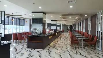 A modern restaurant with a marble floor, red chairs, and a long counter.