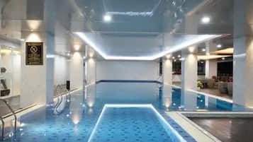 An indoor swimming pool with a blue tiled floor, a central light fixture, and a sign on the wall.