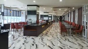 A modern restaurant with a marble floor, red chairs, and a long counter. - Hotel Horison Ultima Entrop (Jayapura)