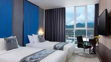 Une chambre d’hôtel avec deux lits, une télévision, un bureau avec une chaise et une grande fenêtre donnant sur la ville.