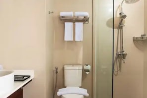 A bathroom with a toilet, a glass-enclosed shower, and a towel rack with two towels. - Hotel Horison Ultima Entrop (Jayapura)