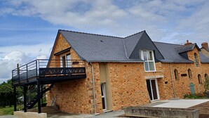 A stone building with a balcony, a staircase, and a small garden area. - Logis de la Provosterie - CROCUS (Ahuille)
